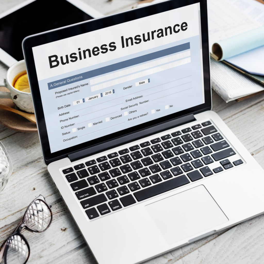 Business Insurance policy displayed on a laptop screen, sitting on a desk with other office items.
