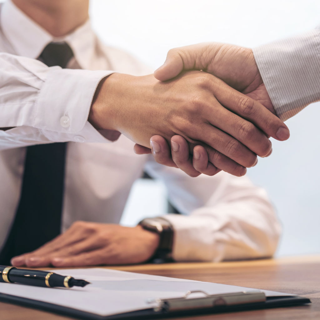 Two businessmen shaking hands with a contract on the table
